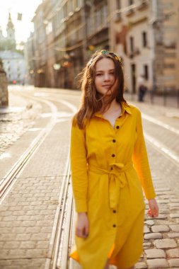 Şehir caddesinde sarı elbiseli güzel bir kız. Avrupalı bir kadının yaz dönemi portresi
