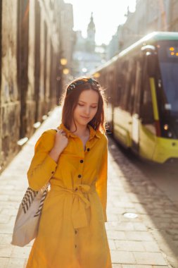 Eski şehir caddesinde yaz kıyafetleri içinde şık bir kız. Genç Avrupalı kadın, yaz dönemi sarı renkli portresi