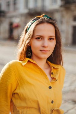 Eski şehir caddesinde yaz kıyafetleri içinde şık bir kız yürüyor. Yaz dönemi sarı renkli genç kadın portresi