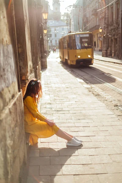 Yazlık gömlekli şık bir kız. Eski şehrin arka planında sarı kıyafetli kadın portresi