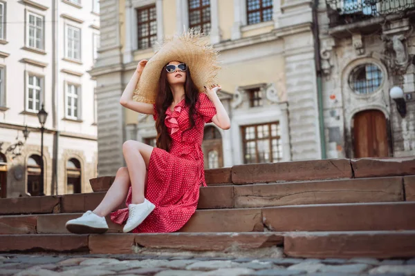 夏季时尚 穿着红圆点裙 草帽和白运动鞋坐在楼梯上的时髦姑娘 — 图库照片