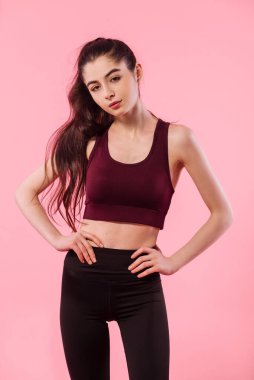 Renkli pembe arka planda şık spor giyimli atletik bir kızın stüdyo portresi. Spor, sağlıklı yaşam tarzı