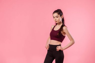 Renkli pembe arka planda spor kıyafetli atletik bir kız. Spor, sağlıklı yaşam tarzı. Güzel spor modelinin stüdyo portresi