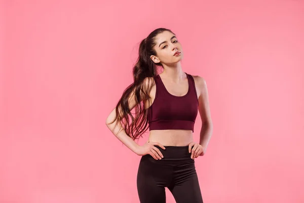 Sport life, fitness model in sporty outfit on pink background. Athletic sportswoman studio portrait