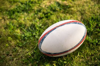 Ragbi topu Gilbert, futbol sahasında, ragbi maçı için yeşil çimlerle. Topa odaklan, arka planda spor sahası.