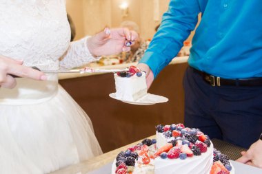 Gelin ve damat bir düğün partisinde iki katlı kremalı beyaz ve mavi bir pasta kestiler. Yaban mersinli kek..