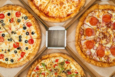 Kare kutularda dört farklı pizza var. Et ve vejetaryen pizza. Üst görünüm.