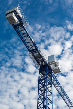 Bulutlu güzel mavi gökyüzüne karşı yükselen mavi vinç. Dikey fotoğraf, aşağıdan görünüm.