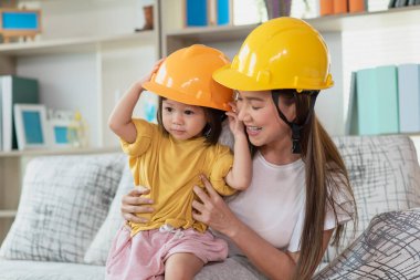 Asyalı anne ve çocuk kızı sarı mühendis kaskı, eğitim ve meslek konsepti takıyor.