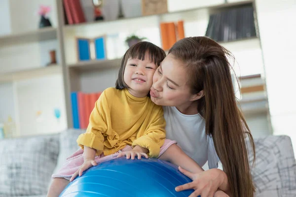 幸せなアジアの子供は体操ボールを楽しんで 自宅で母親と一緒に練習をしています — ストック写真