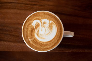 Tahta masada bir fincan sıcak latte sanat kahvesi.