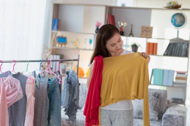 Asyalı ev hanımı soyunma odasından elbise seçiyor.