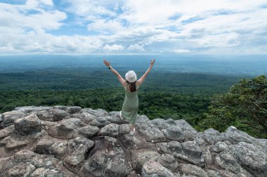 Young Asian women traveler hiking on mountains, raising hands at Lan Hin Pum, Phu hin Rong Kla National Park, Phitsanulok province, Thailand
