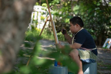 Tuvalde suluboya boyayla resim yapan sevimli, mutlu Asyalı bir çocuk. Çocuk yaratıcı aktiviteler, sanat eğitimi.