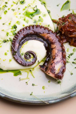 Izgara ahtapot dokunaçları sos ve patates püresiyle servis edilir.