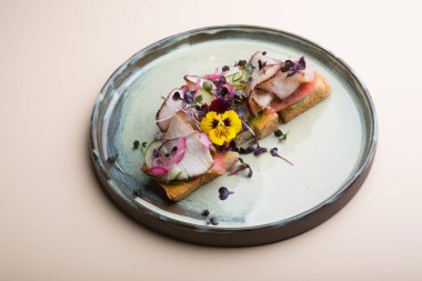 Çiçekler ve mikro yeşille süslenmiş jambonlu tost.