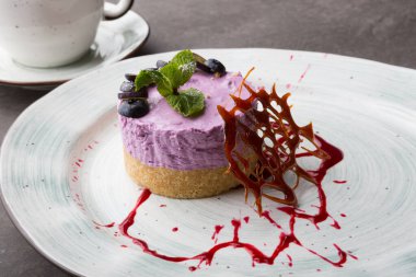 Kafe masasında çay ile süslenmiş taze yaban mersinli kek.