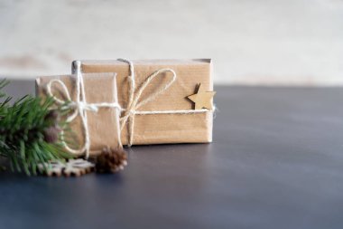 Noel ve sıfır atık, çevre dostu ambalaj. Tahta kar taneleriyle el sanatları kağıdına sarılmış hediyeler ve ahşap bir arka planda yıldız. Ekolojik Noel tatili konsepti, ahşaplı eko dekor