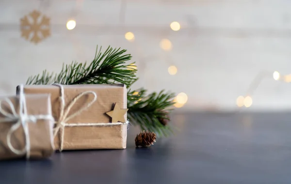 Noel ve sıfır atık, çevre dostu ambalaj. Tahta kar taneleriyle el sanatları kağıdına sarılmış hediyeler ve ahşap bir arka planda yıldız. Ekolojik Noel tatili konsepti, ahşaplı eko dekor