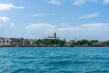Zanzibar 'daki Stone Town' un ufuk çizgisi sudan görülüyor. Bulutlarla güneşli bir gün. Turkuaz Hint Okyanusu ile seyahat kavramı