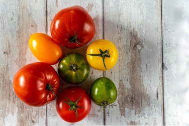 Beyaz ahşap arka planda renkli domatesler. düz çekim