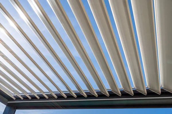 Metalik yapıdan geçen güneş ışınları ile son moda açık hava pergola.