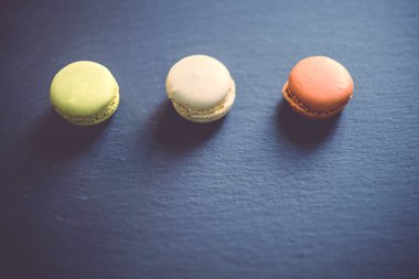 Koyu, karamsar bir çikolata, karamel ve vanilyalı badem kurabiyesinin koyu gri bir beton desenli arka planda sıralanması..