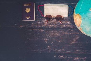 World map and items on wooden background, flat lay. summer travel wanderlust concept, space for text. map camera sunglasses passport phone pen mask book on wooden background top view. planning vacation concept.
