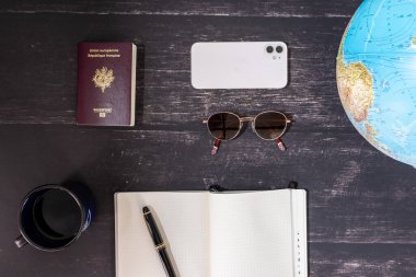 World map and items on wooden background, flat lay. summer travel wanderlust concept, space for text. map camera sunglasses passport phone pen mask book on wooden background top view. planning vacation concept.