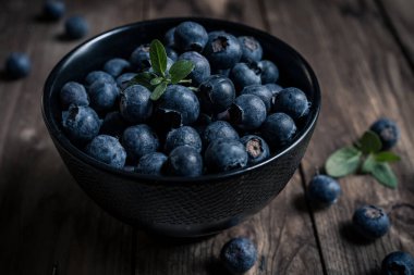 Tahta bir masada siyah bir kasede taze yaban mersinlerinin yakın çekimi. yakın çekim görünümü