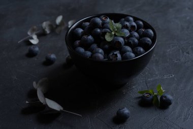 Siyah bir levhada siyah bir kasede taze yaban mersinlerinin yakın plan çekimi. yakın çekim görünümü