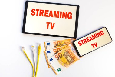 Ekrandaki metni gösteren tabletler ve akıllı telefonlar, banknotlar, veri kabloları, para ve elektrik prizleri. Televizyon programlarının maliyeti ve tüketimi. 