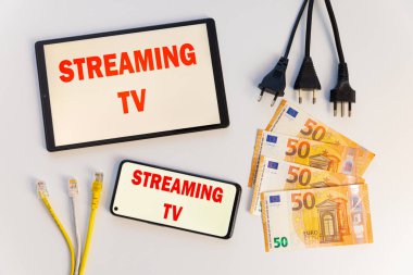 Ekrandaki metni gösteren tabletler ve akıllı telefonlar, banknotlar, veri kabloları, para ve elektrik prizleri. Televizyon programlarının maliyeti ve tüketimi. 