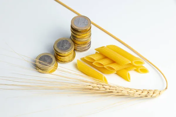 Yanında makarna (pennette) ve bozuk para olan buğday kulağı. Buğday, makarna ve ürün fiyatlarında artış.
