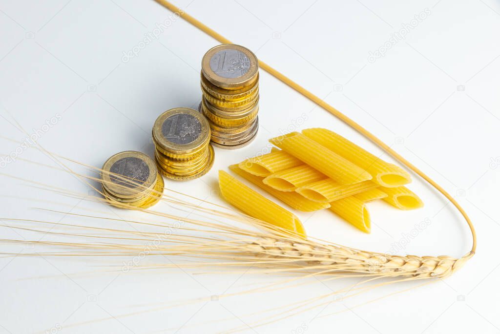 Ear of wheat, with pasta (pennette) and coins next to it. Increase in the price of wheat, pasta and products.