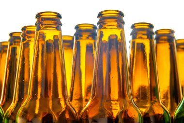 Boş cam bira şişeleri, kahverengi, yan yana dizilmiş ve ışığa karşı fotoğraflanmış..