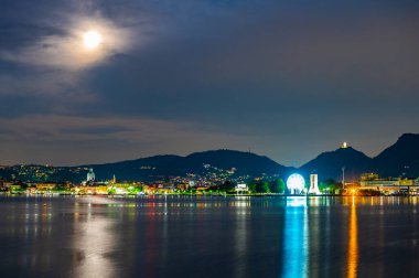 The city of Como, photographed in the evening, with the lakefront, the cathedral, and the surrounding mountains.