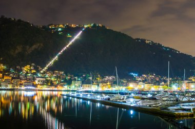 The city of Como, photographed in the evening, with the lakefront, the cathedral, and the surrounding mountains.