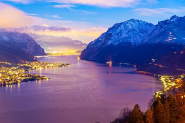Panorama, Como Gölü 'nün Lecco kıyısını bir kış akşamı, bulutlar ve karlı dağlarla gösteriyor..