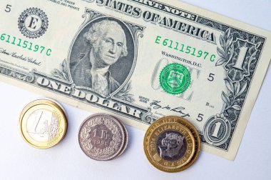 Euro, Dollar, Pound and Swiss Franc coins on white surface. Value of Swiss Franc, Dollar, Pound and Euro, exchange rate trend.