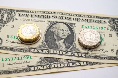 Coins of Euro, Dollar, and Swiss Franc on white surface. Value of Swiss Franc, Dollar, and Euro, exchange rate trend.