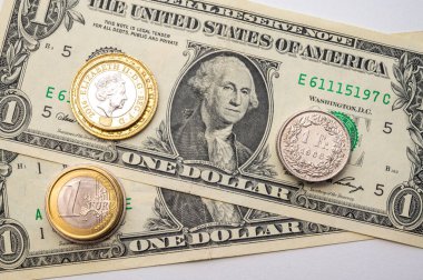 Euro, Dollar, Pound and Swiss Franc coins on white surface. Value of Swiss Franc, Dollar, Pound and Euro, exchange rate trend.
