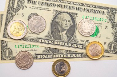 Euro, Dollar, Pound and Swiss Franc coins on white surface. Value of Swiss Franc, Dollar, Pound and Euro, exchange rate trend.