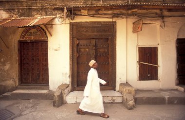 Tanzanya 'nın Zanzibar Adası' ndaki Taş Kasaba 'nın geleneksel ahşap kapısındaki yerel bir adam. Tanzanya, Zanzibar, Taş Şehir, Ekim 2004