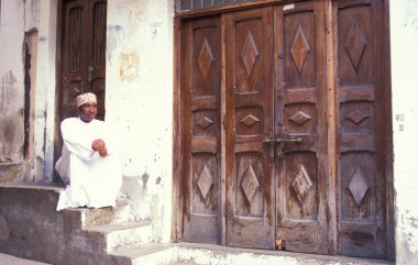 Tanzanya 'nın Zanzibar Adası' ndaki Taş Kasaba 'nın geleneksel ahşap kapısındaki yerel bir adam. Tanzanya, Zanzibar, Taş Şehir, Ekim 2004