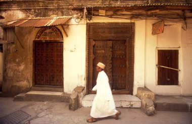 Tanzanya 'nın Zanzibar Adası' ndaki Taş Kasaba 'nın geleneksel ahşap kapısındaki yerel bir adam. Tanzanya, Zanzibar, Taş Şehir, Ekim 2004