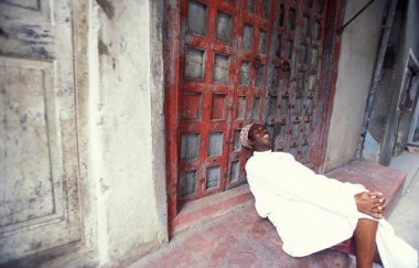 Tanzanya 'nın Zanzibar Adası' ndaki Taş Kasaba 'nın geleneksel ahşap kapısındaki yerel bir adam. Tanzanya, Zanzibar, Taş Şehir, Ekim 2004