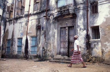 Tanzanya 'nın Zanzibar Adası' ndaki Taş Kasaba 'nın geleneksel ahşap kapısındaki yerel bir adam. Tanzanya, Zanzibar, Taş Şehir, Ekim 2004