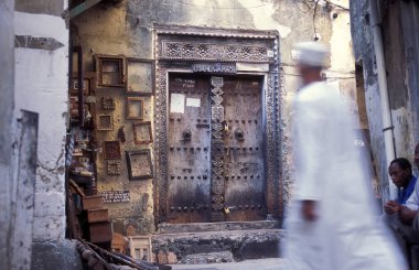 Tanzanya 'nın Zanzibar Adası' ndaki Taş Kasaba 'nın geleneksel ahşap kapısındaki yerel bir adam. Tanzanya, Zanzibar, Taş Şehir, Ekim 2004