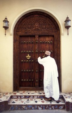 Tanzanya 'nın Zanzibar Adası' ndaki Taş Kasaba 'nın geleneksel ahşap kapısındaki yerel bir adam. Tanzanya, Zanzibar, Taş Şehir, Ekim 2004